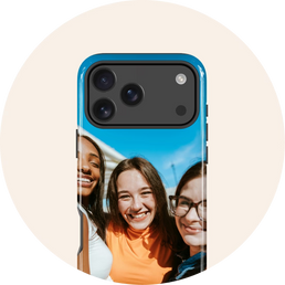 A custom printed phone case with a blue bumper frame, featuring a photo of three smiling young women, shown on a phone mockup against a light cream circular background.