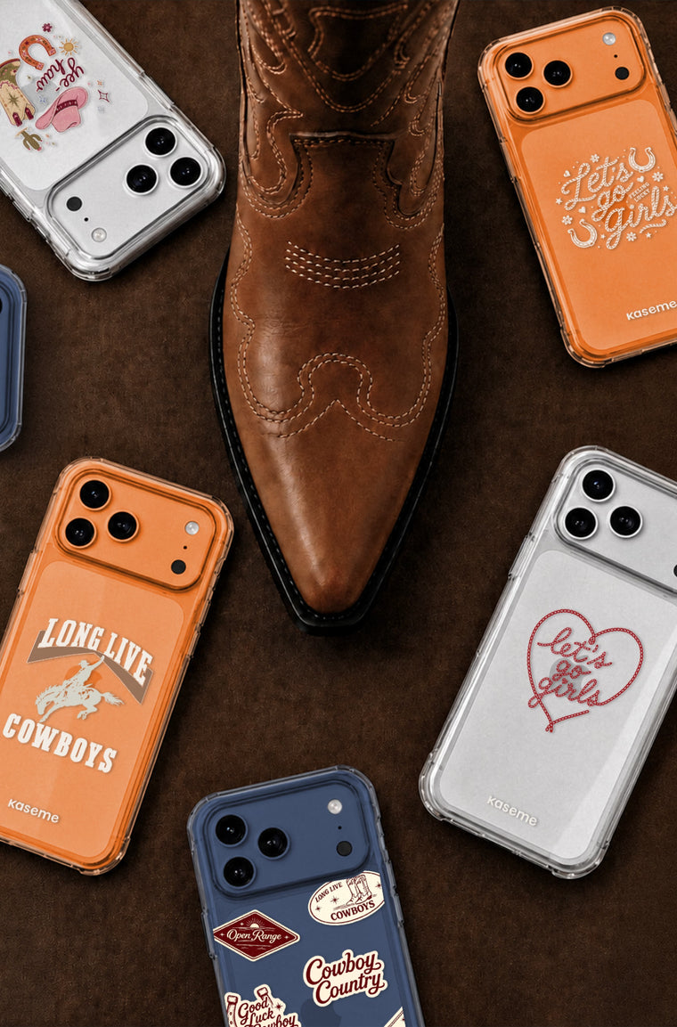 A styled flat-lay featuring a brown leather cowboy boot centered among several phone cases on a dark brown textured background. The cases include orange, clear, navy, and white designs with western-themed graphics such as 'Long Live Cowboys, and a red heart reading 'Let's go girls'.