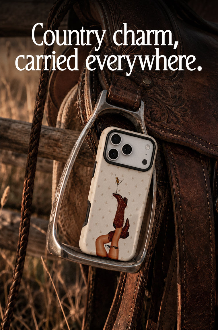 A clear phone case with a western-themed print of a woman's legs in cowboy boots, hanging from a leather saddle on a rustic fence. The image has the text 'Country charm, carried everywhere.